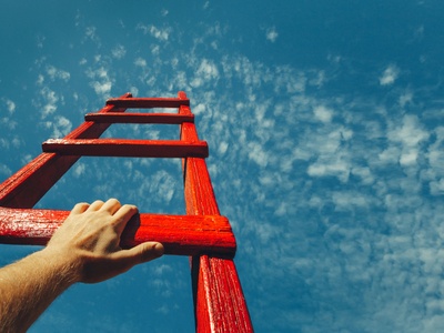 hands climbing a red ladder into the sky